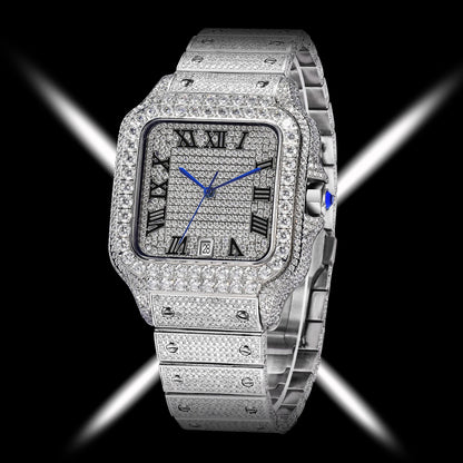 A luxury watch with a silver-toned rectangular case and integrated bracelet, heavily embellished with sparkling pavé stones. The watch face features black Roman numeral hour markers, silver hands, and a small blue cabochon accent on the crown, set against a black background with dramatic white light streaks.