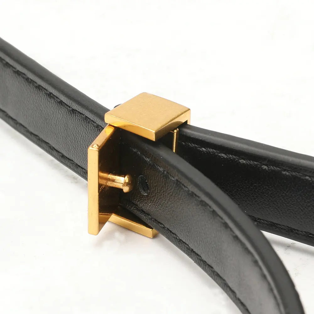 A close-up of a black leather belt with a polished gold-tone metal buckle, set against a clean white background.