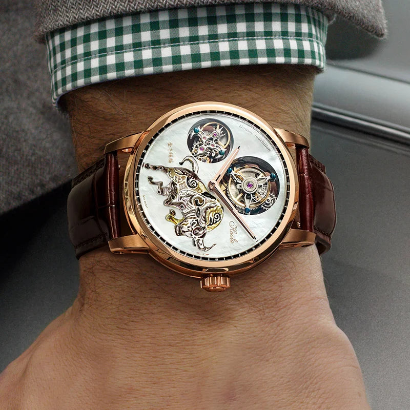 A wristwatch with a rose gold case, white skeleton dial, and dark brown leather strap, shown worn on a person's wrist.