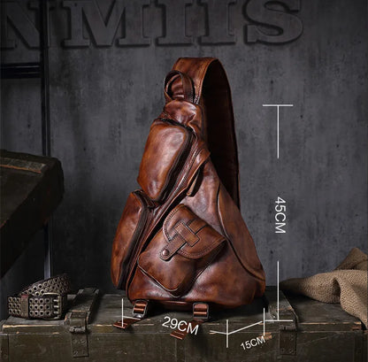 A brown leather sling backpack displayed on a rustic wooden crate against a dark gray textured wall, with overlaid dimension lines showing measurements of 45cm height, 29cm width, and 15cm depth.