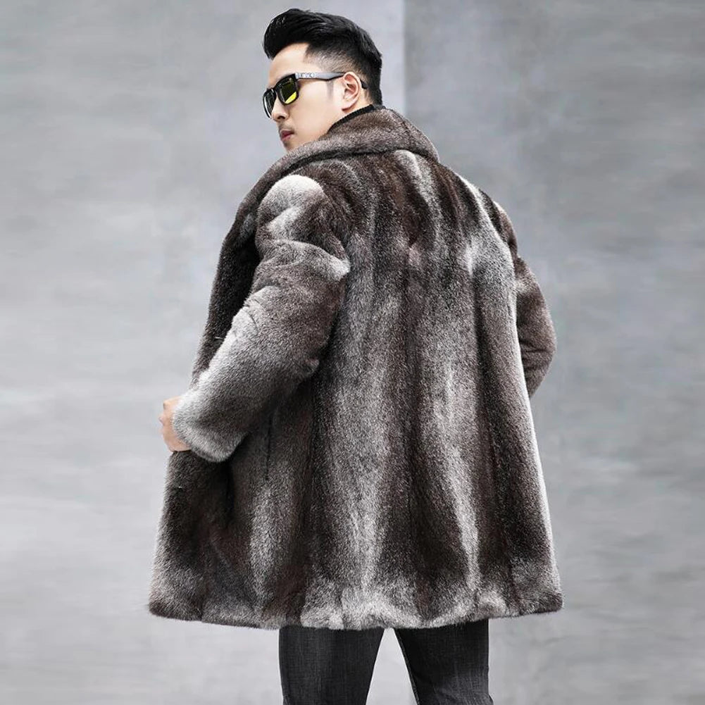A man wearing a dark brown and gray faux fur coat, black sunglasses, and black pants, photographed from the back against a gray concrete wall.