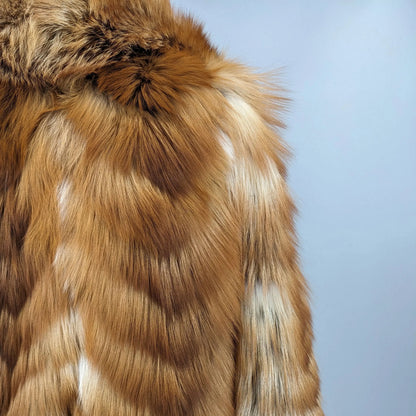 Close-up of a brown and cream patterned faux fur garment, showing the texture and color details against a solid light blue background.