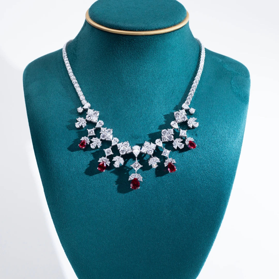 Elegant diamond necklace with red gemstones on a teal mannequin bust.