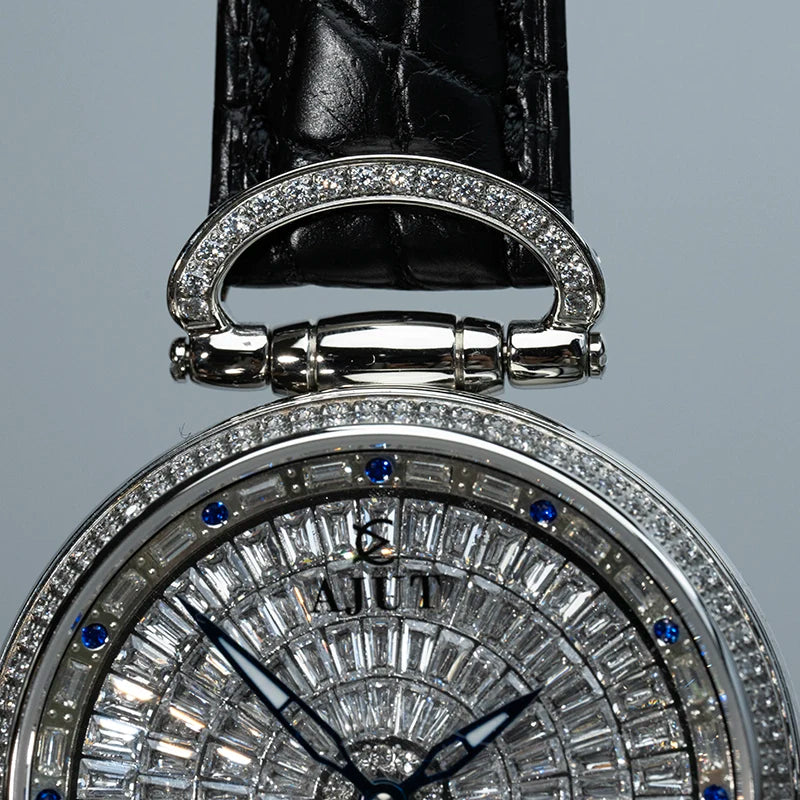 Close-up of a diamond-encrusted watch with a black leather strap on a gray background