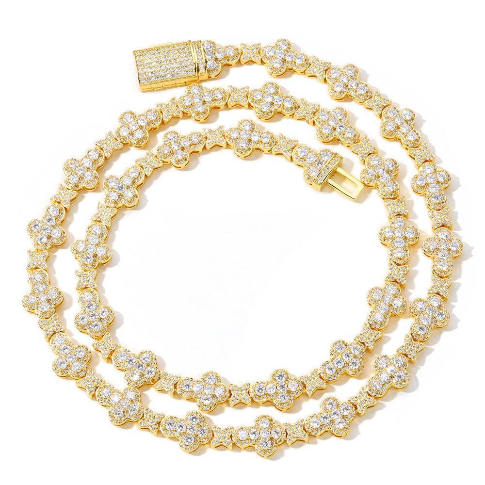 A gold double-strand tennis-style chain necklace heavily embellished with clear pavé stones, arranged in a coiled shape on a white background.