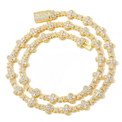 A gold double-strand tennis-style chain necklace heavily embellished with clear pavé stones, arranged in a coiled shape on a white background.