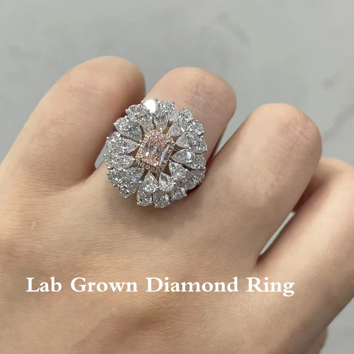 A close-up of a hand wearing a large floral cluster ring made of lab-grown diamonds and a central pink gemstone in a silver-toned setting, with the text 'Lab Grown Diamond Ring' overlaid at the bottom.